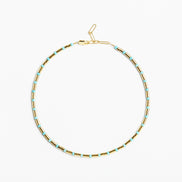 A delicate gold chain necklace with small, evenly spaced light blue beads, displayed in a circular shape against a clean white background.