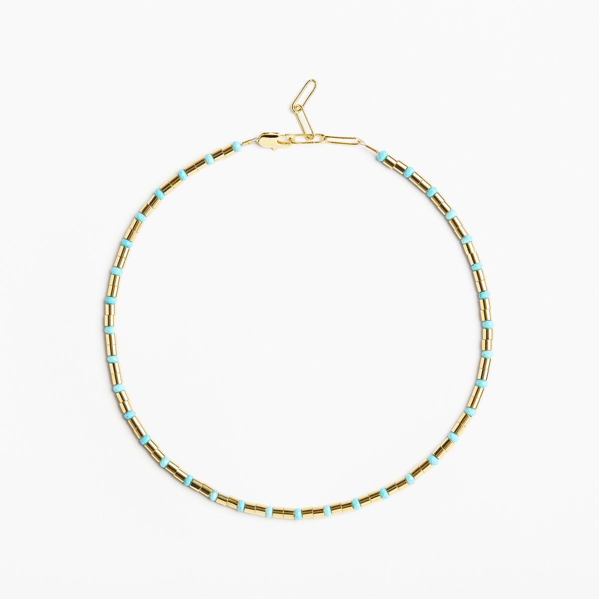 A delicate gold chain necklace with small, evenly spaced light blue beads, displayed in a circular shape against a clean white background.