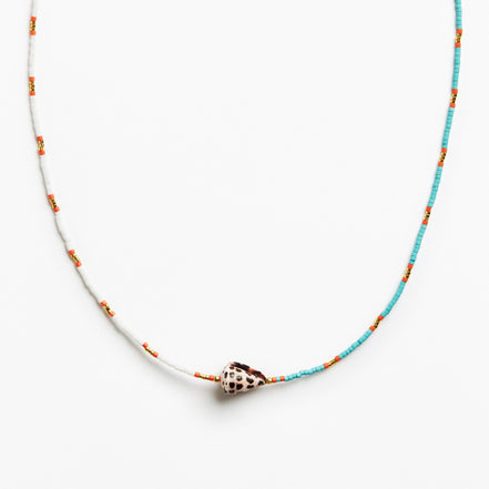 A delicate beaded necklace featuring turquoise blue and white beads with small orange accents, centered with a natural cowrie shell pendant on a clean white background.