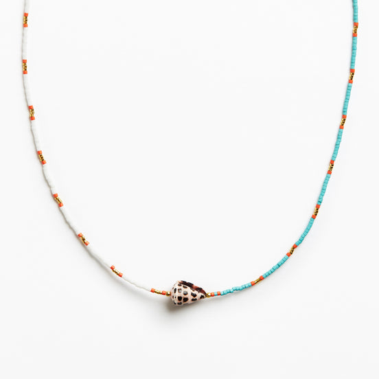 A delicate beaded necklace featuring turquoise blue and white beads with small orange accents, centered with a natural cowrie shell pendant on a clean white background.