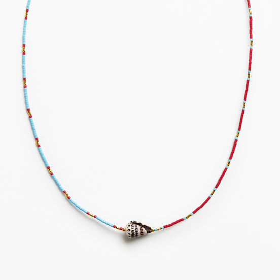 A beaded necklace featuring a light blue and red string with small yellow accents, finished with a silver conch shell pendant, shown against a plain white background.