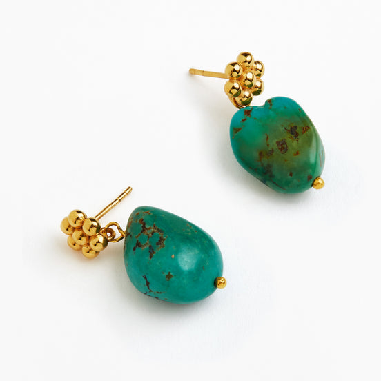A pair of gold-tone dangle earrings featuring organic-shaped turquoise-green stone drops with natural matrix inclusions, displayed on a clean white background.