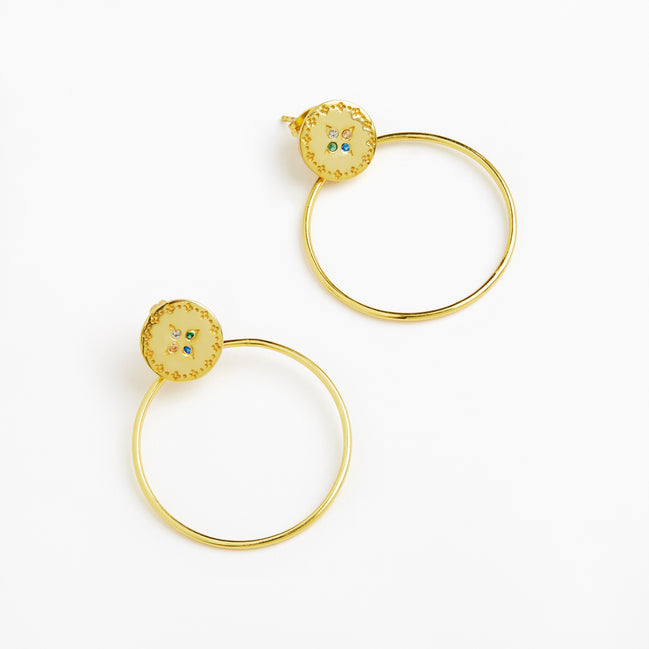 A pair of gold hoop earrings with oval gold studs featuring a scalloped border and small blue and green enamel details, shown on a clean white background.