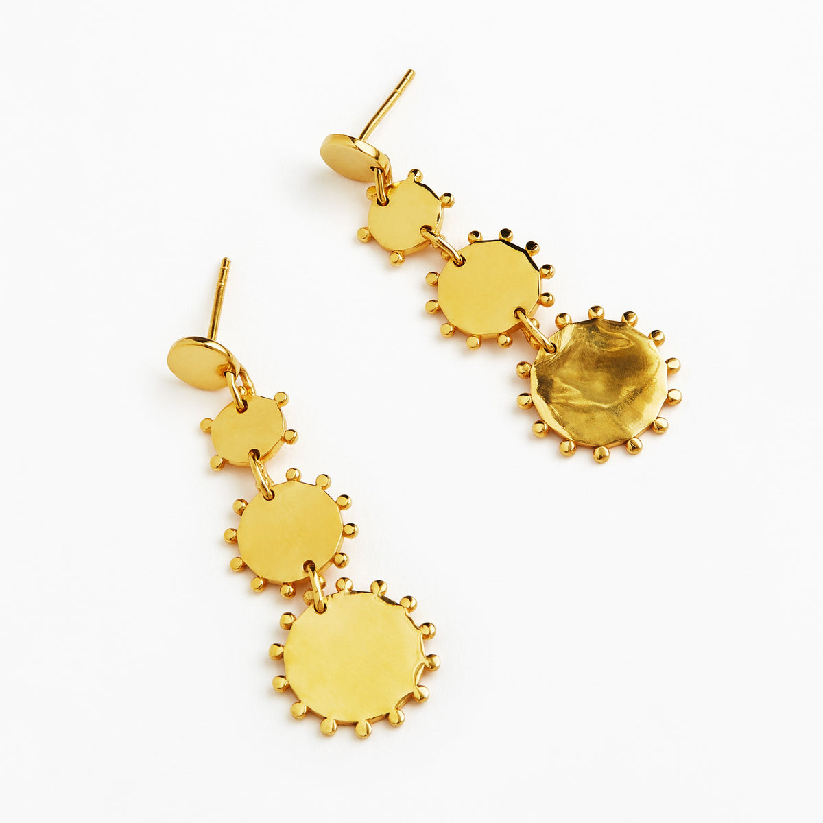 A pair of gold dangle earrings with a series of textured circular disc charms of varying sizes, shown on a plain white background.