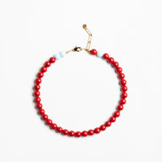 A beaded necklace featuring a continuous strand of glossy red beads, accented by two small light blue beads and a gold-tone lobster clasp, displayed on a clean white background.