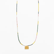 A delicate beaded necklace with a textured gold square pendant, featuring small beads in yellow, green, pink, and white, displayed against a clean white background.