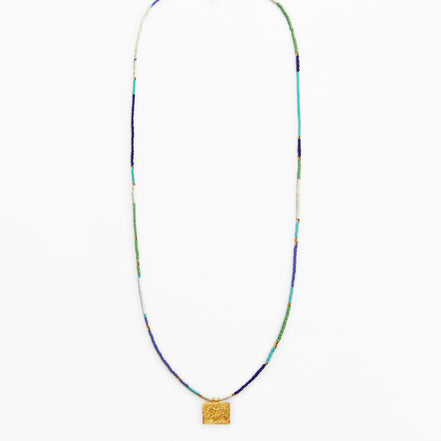 A long beaded necklace with a textured gold square pendant, featuring beads in blue, green, white, and gold.
