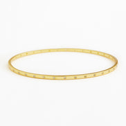 A thin gold bangle bracelet with small clear rhinestones set along the front edge, displayed on a clean white background.