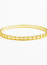 A thin yellow gold bangle bracelet with a row of small circular cutouts along the front, shown on a plain white background.