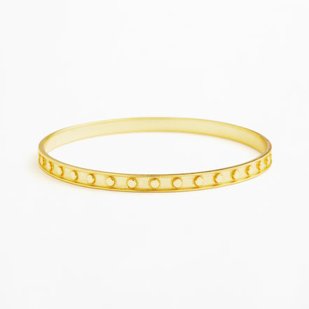 A thin yellow gold bangle bracelet with a row of small circular cutouts along the front, shown on a plain white background.