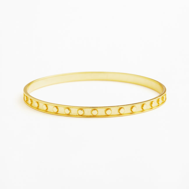 A thin yellow gold bangle bracelet with a row of small circular cutouts along the front, shown on a plain white background.