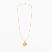 A delicate gold chain necklace with a small round ship's wheel pendant, displayed against a clean white background.