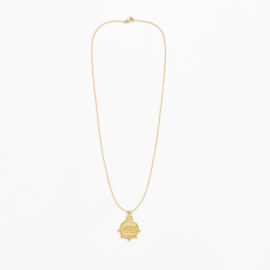 A delicate gold chain necklace with a small round ship's wheel pendant, displayed against a clean white background.