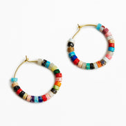 A pair of gold-tone hoop earrings decorated with small, colorful cylindrical beads in various patterns and colors, set against a plain white background.