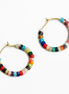 A pair of gold-tone hoop earrings decorated with small, colorful cylindrical beads in various patterns and colors, set against a plain white background.