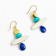 A pair of bohemian dangle earrings featuring gold-tone fishhook wires, white oval beads, turquoise and gold round beads, and faceted blue teardrop beads, displayed on a clean white background.