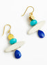 A pair of bohemian dangle earrings featuring gold-tone fishhook wires, white oval beads, turquoise and gold round beads, and faceted blue teardrop beads, displayed on a clean white background.
