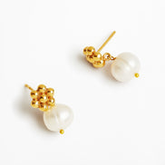 A pair of gold and pearl drop earrings on a clean white background. Each earring features a cluster of polished gold beads at the top and a large, irregular white freshwater pearl hanging below, secured with a tiny gold bead accent.