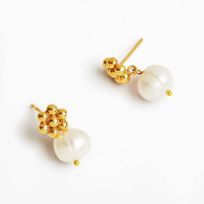 A pair of gold and pearl drop earrings on a clean white background. Each earring features a cluster of polished gold beads at the top and a large, irregular white freshwater pearl hanging below, secured with a tiny gold bead accent.