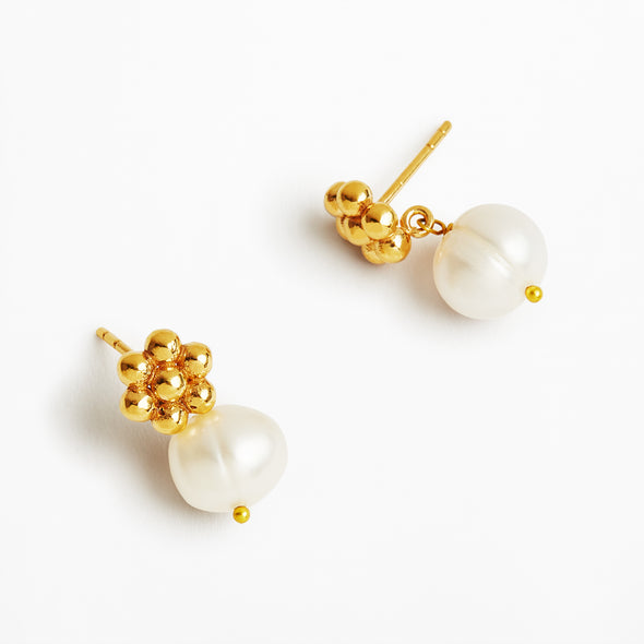 A pair of gold and pearl drop earrings on a clean white background. Each earring features a cluster of polished gold beads at the top and a large, irregular white freshwater pearl hanging below, secured with a tiny gold bead accent.