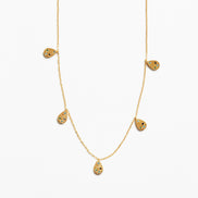 A delicate gold chain necklace featuring five small teardrop-shaped pendants, each decorated with tiny black and yellow inlay details, set against a plain white background.